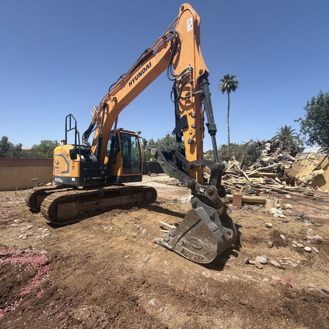 Tracked excavator fitted with a hydraulic breaker working a cleared demolition site