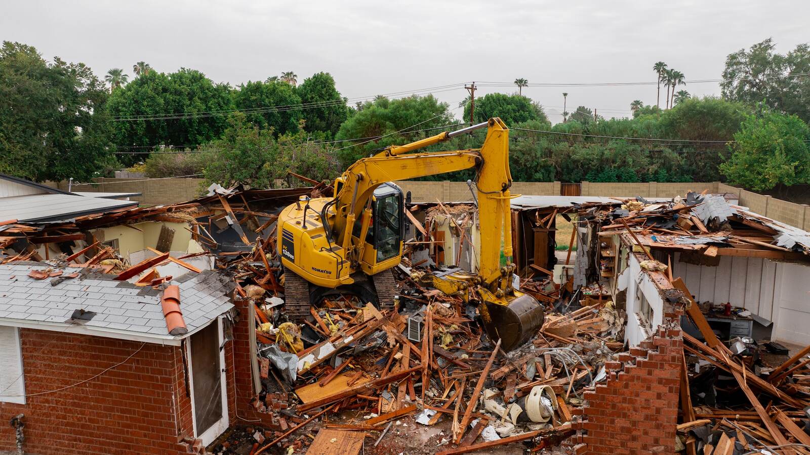 Overhead view of controlled residential demolition by Kogan LLC, excavator working the roofline