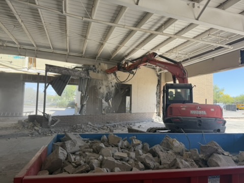 Excavator taking down an interior wall in a commercial unit