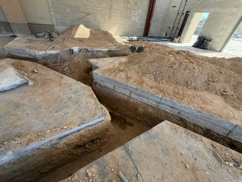 Concrete floor cut and trenched, spoil cleared to the edges
