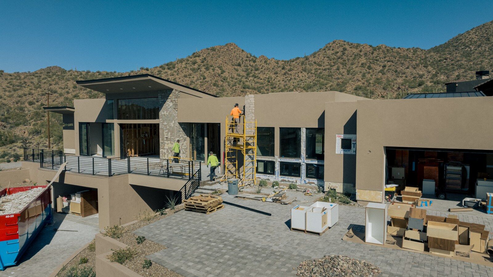 Exterior of a desert home under construction by Kogan LLC with crew on site