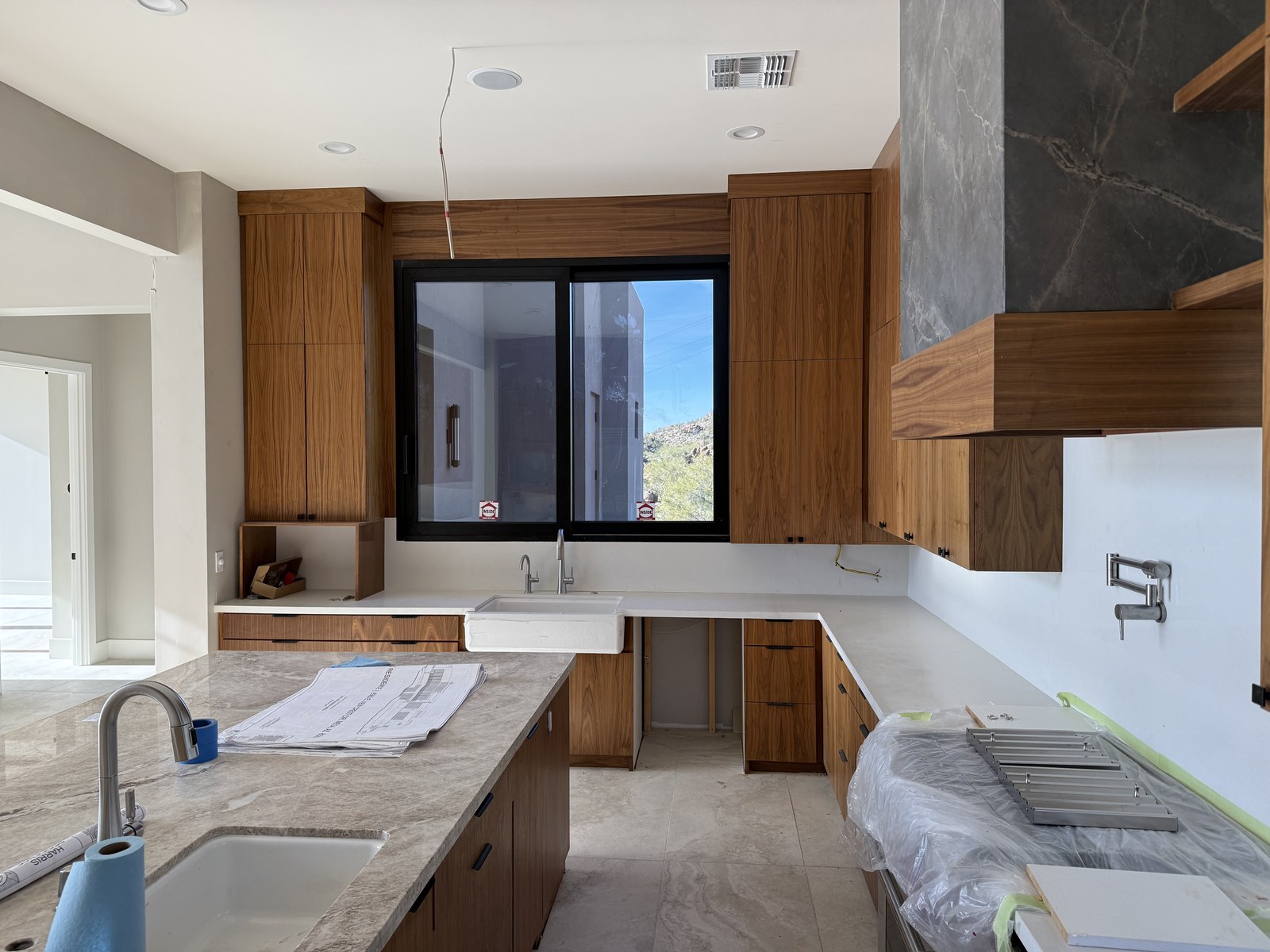 A kitchen with walnut cabinetry, a stone range hood surround and a desert view window