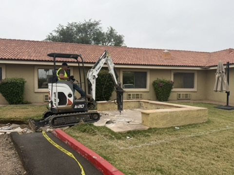 Mini excavator removing a front yard structure at a Phoenix home