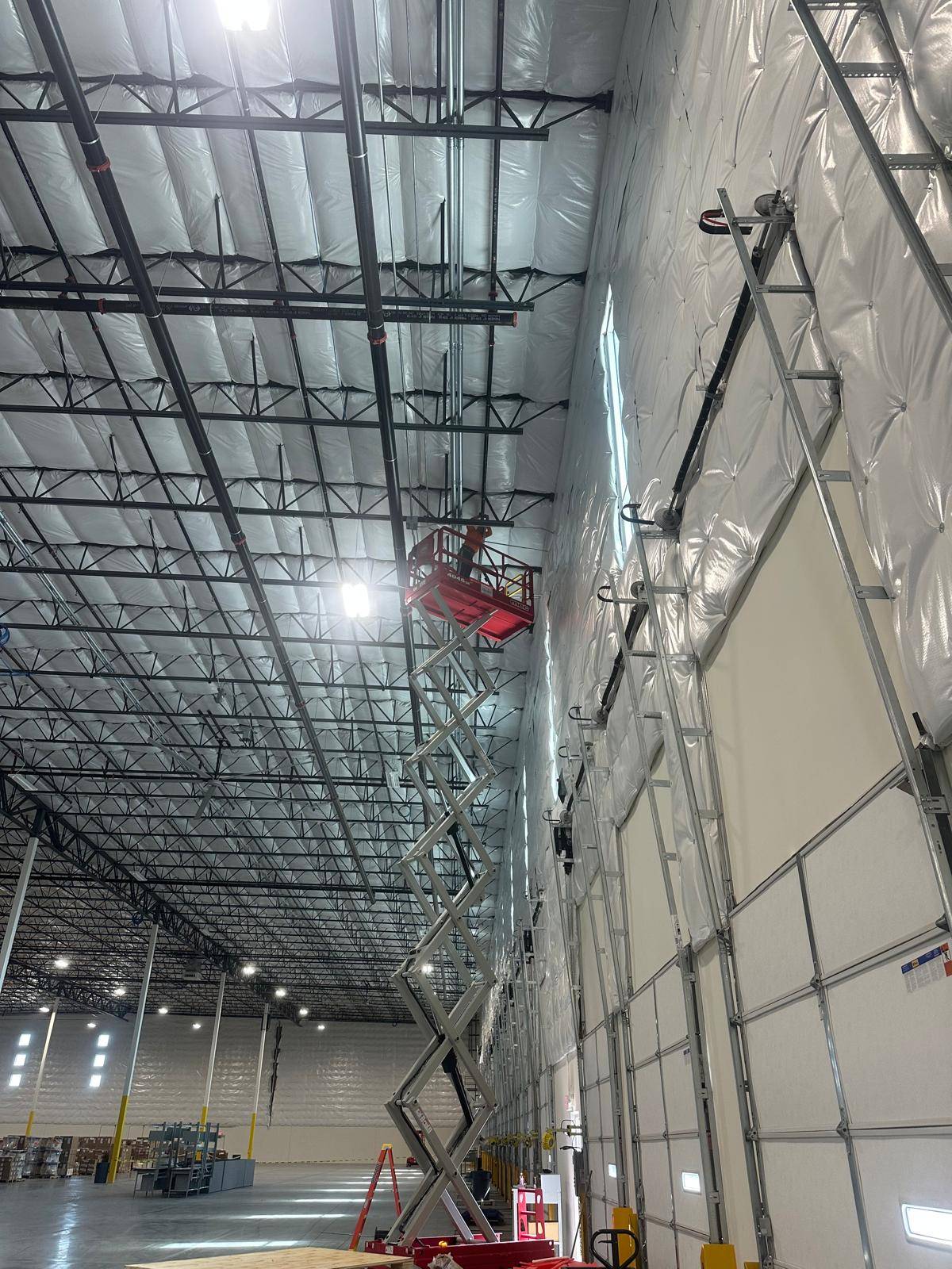 A scissor lift beside a new interior wall going up inside a warehouse build-out in Phoenix, Arizona