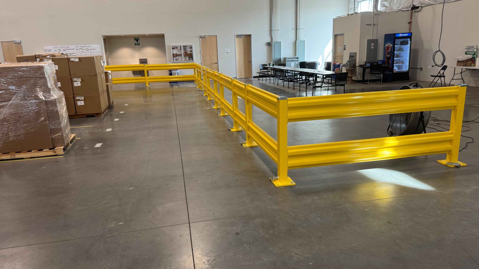 Steel guardrail run separating a warehouse floor from the break area