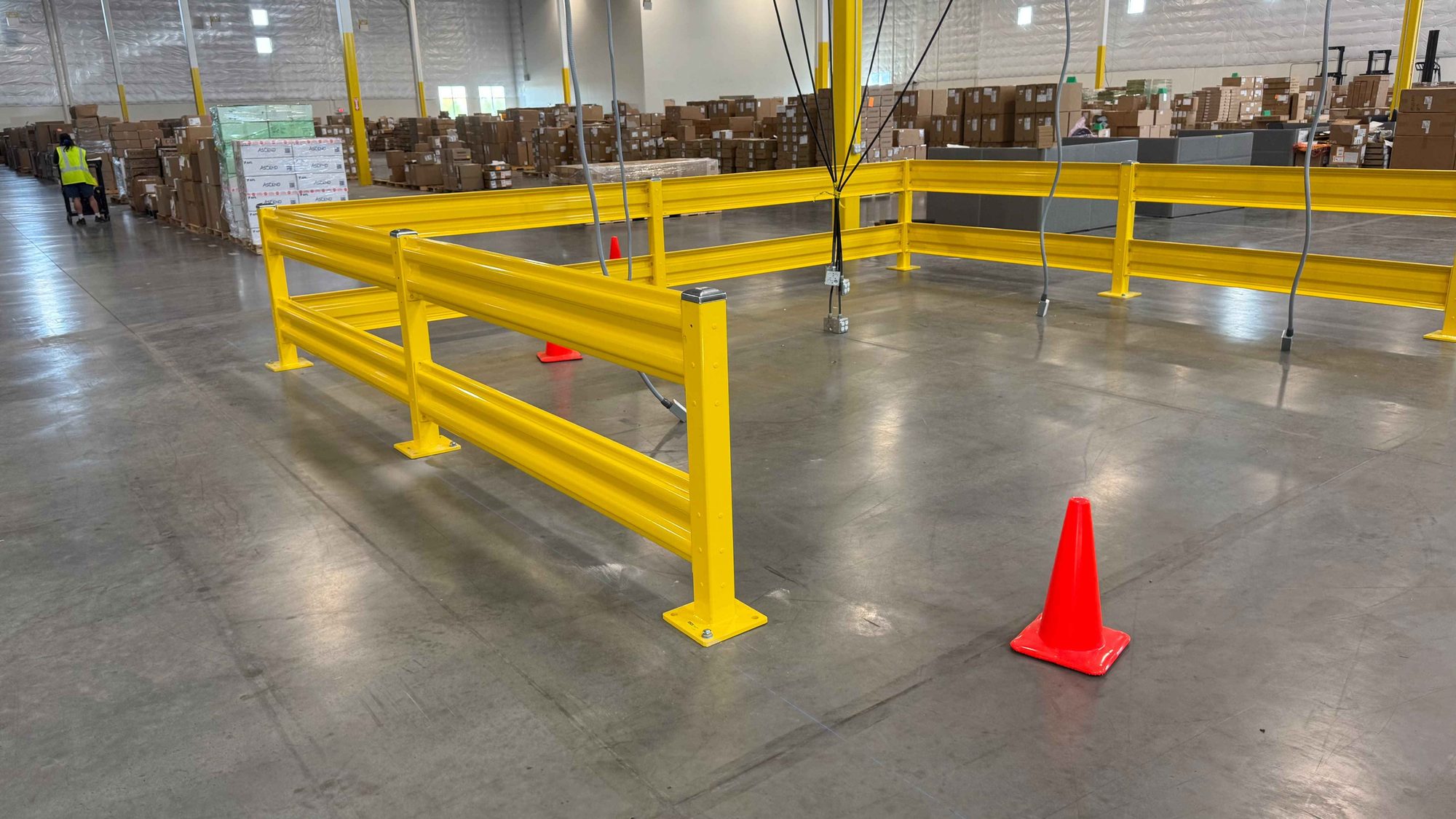 Steel guardrail enclosure around overhead equipment cable drops in a warehouse
