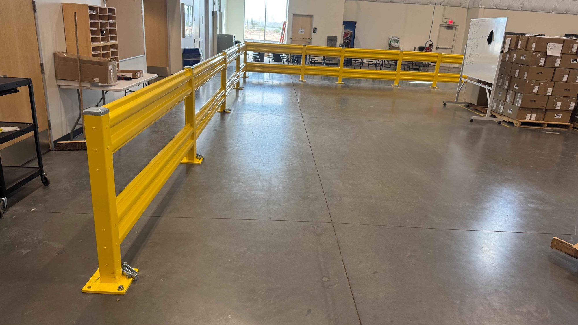 Long steel guardrail run anchored to the slab along a warehouse office wall